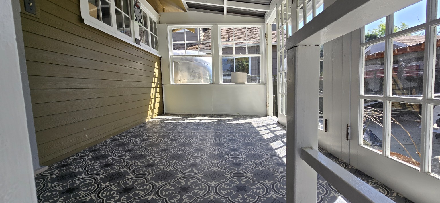 Patterned black-and-white flooring in a sunlit enclosed porch